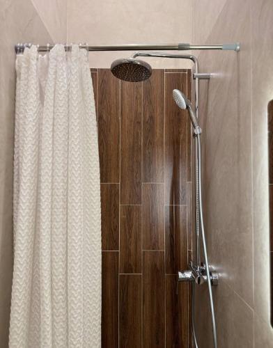 a shower with a white shower curtain and a shower head at The Palm hotel & spa in Almaty
