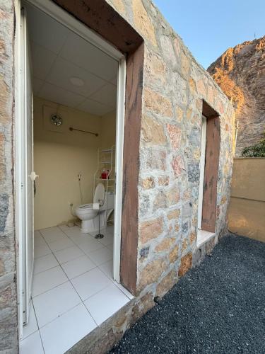 a bathroom with a toilet and a stone wall at Daftah Valley Farmhouse in Daftah