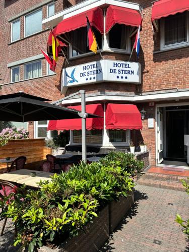 a restaurant with tables and umbrellas in front of a building at Hotel De Stern in Scheveningen