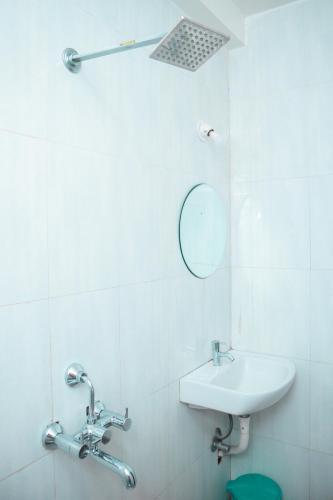 a white bathroom with a sink and a mirror at Dip Holidays Resort in Shānti Niketan