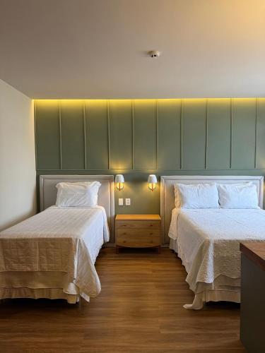 a room with two beds with white sheets at Pousada Macamirim in Macaíba
