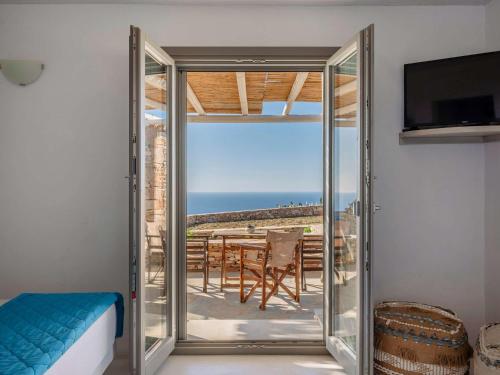 a room with a sliding glass door with a view of the ocean at Moniasma Rustic Stone House in Folegandros in Ano Meria