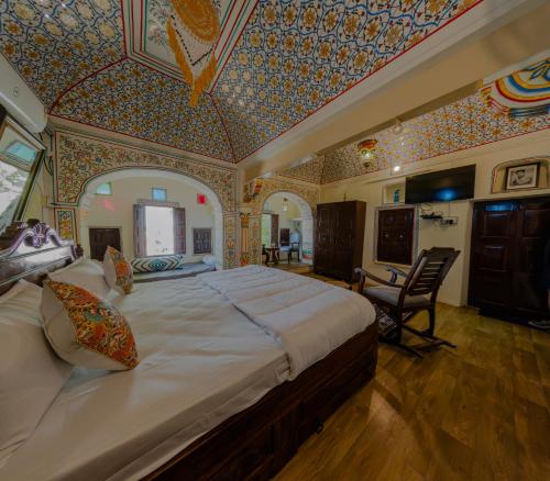 ein Schlafzimmer mit einem großen Bett und einer farbenfrohen Decke in der Unterkunft Jeevan Haveli Heritage Hotel & Museum in Nawalgarh