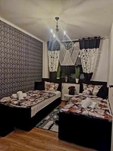 a bedroom with two beds and a chandelier at Apartament Marzenie in Siechnice