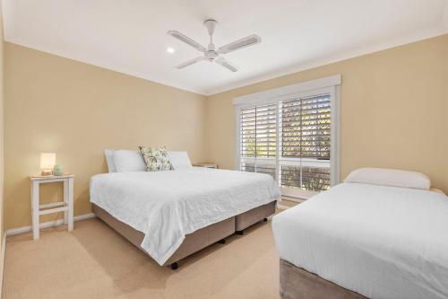 een slaapkamer met twee bedden en een plafondventilator bij Waterfront entertainers dream with private beach in Gold Coast