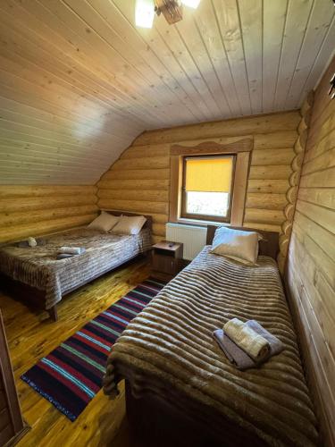 two beds in a room with wooden walls at Сонячна долина in Negrovets