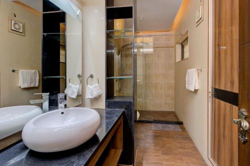 Un baño con lavabo y ducha de cristal. en The Grand Rustam Villa, en Gurgaon