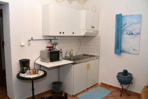 Una pequeña cocina con fregadero y microondas. en ΑΡΣΙΝΟΗ apartments1, en Arachova