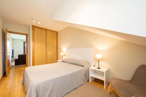 una camera da letto con un letto bianco e una sedia di Apartamento Luz de Poniente a Llanes