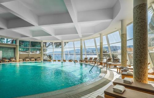 a pool in a hotel with chairs and windows at Valamar Sanfior Hotel & Casa in Rabac