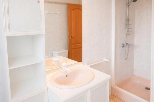 un bagno bianco con lavandino e doccia di Gîte le Platane a Montagnac