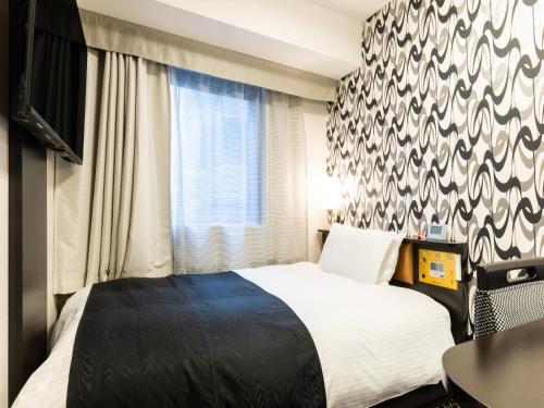 a hotel room with a bed and a window at APA Hotel Kanazawa Chuo in Kanazawa