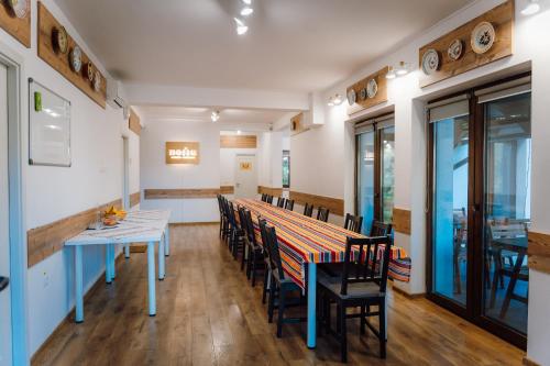 a dining room with a long table and chairs at Pensiunea Nossa Panzió in Corunca