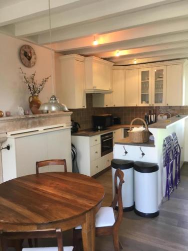 a kitchen with white cabinets and a wooden table at La bergerie - Point de vue sur la Creuse in Ceaulmont