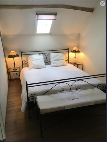 a bedroom with a bed with two lamps and a window at La bergerie - Point de vue sur la Creuse in Ceaulmont