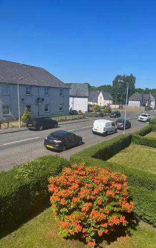 a street with cars driving down a road with flowers at Loch Lomond Apartment in Alexandria
