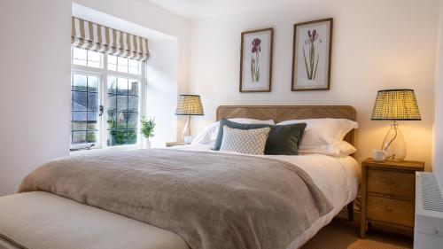 een slaapkamer met een bed met twee lampen en een raam bij Oak Cottage in Swerford