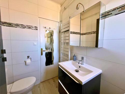 Un baño con lavabo, inodoro y espejo. en Brise Marine - Appartement 2 chambres avec balcon, vue mer & parking privé à 30 m de la plage, en Palavas-les-Flots
