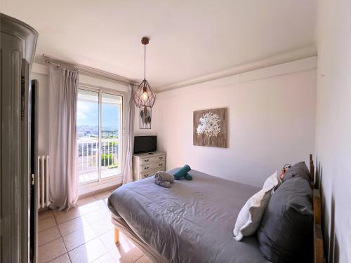 Un dormitorio con una cama y un televisor y una ventana. en Brise Marine - Appartement 2 chambres avec balcon, vue mer & parking privé à 30 m de la plage, en Palavas-les-Flots