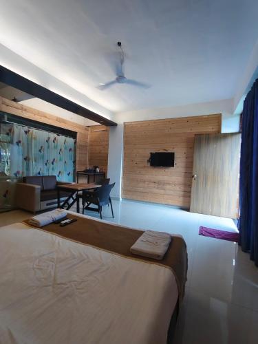 a bedroom with a large bed and a dining room at Pinewood mahabaleshwer in Panchgani
