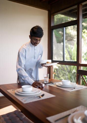 Eine Frau steht an einem Tisch mit einem Teller in der Unterkunft LohonoStays Villa Amani 8B in Coonoor