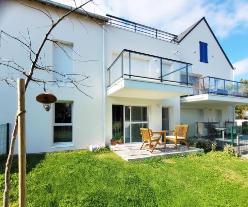 een wit huis met een tafel en stoelen bij Ty ravissant - Les Gîtes de la Côte d'Amour in Le Croisic