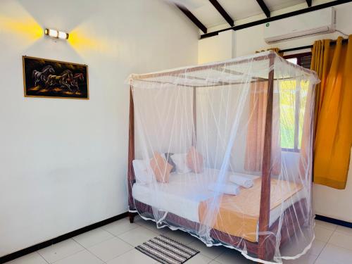 a bedroom with a bed covered in mosquito net at Harshi Guest House in Matara