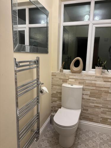 a bathroom with a toilet and two windows at Entire House, Parking, Facilities, sleeps up to 6, suitable for contractors, families or NHS in Liverpool