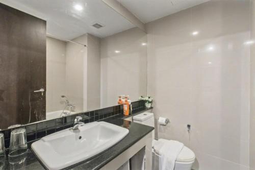 a bathroom with a sink and a toilet and a mirror at Kris - Modern Spacious 2 Bedrooms Condo with Pool in Patong Beach