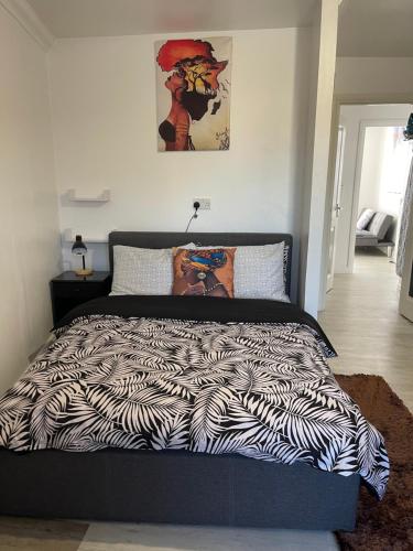 a bed with a black and white comforter in a bedroom at Bowery Apartment - 2 Bedrooms 1st floor in Dagenham