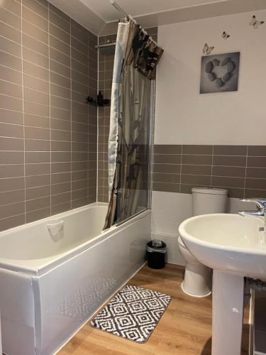 a bathroom with a tub and a sink and a toilet at Bowery Apartment - 2 Bedrooms 1st floor in Dagenham