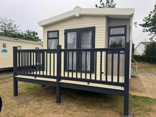 a tiny house with a black railing on a yard at Luxury 2 bedroom Caravan Pets stay Free in Hunstanton