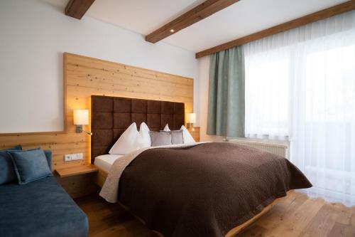 a bedroom with a bed and a window and a couch at Bergnest die Frühstückspension in Katschberghöhe