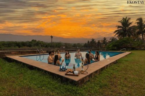 a group of people in a swimming pool at sunset at EKOSTAY - Utopian Villa with Jacuzzi in Candolim