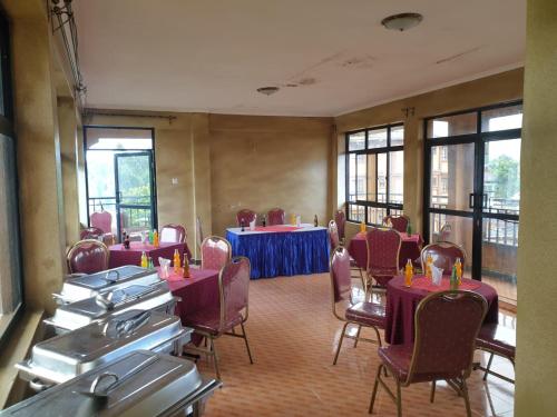 Habitación con mesas, sillas y ventanas de color púrpura. en Oldoiyo Lengai Resort, en Karatina