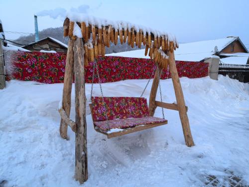 een schommel in een tuin bedekt met sneeuw bij Snow Town Jingbei Hotel Erlanghe Scenic Area Branch in Yushu
