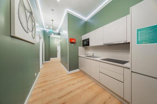 een keuken met witte kasten en groene muren bij HOME1 - Belvedere Boutique Hostel in Wenen