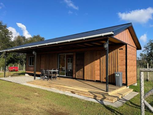 Una cabaña de madera con terraza y mesa. en Cabaña moderna y equipada en parcela en Valdivia, en Valdivia