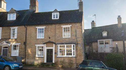 ein altes Backsteinhaus mit einem Auto davor geparkt in der Unterkunft Bell Cottage in Charlbury