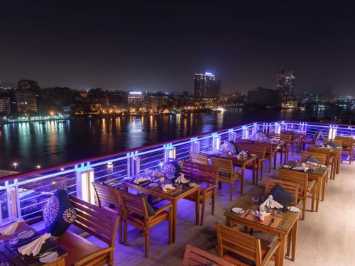 a row of tables and chairs on a deck at night at Novotel Cairo El Borg in Cairo
