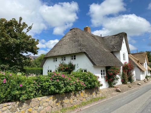 a thatched cottage with flowers on a stone wall at Haus Oevenum in Oevenum
