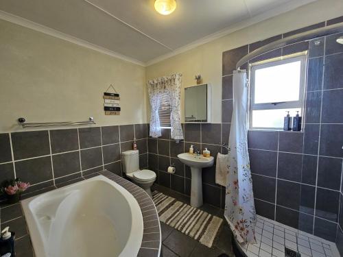 Un baño con bañera, inodoro y lavabo. en Spacious Family 2-Bedroom Apartment, en Port Alfred