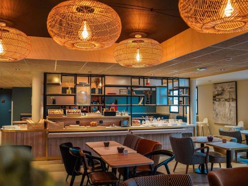 ibis Bayeux Port En Bessin في بورت-أون-بيسين-هوباين: مطعم به طاولات وكراسي واضاءات