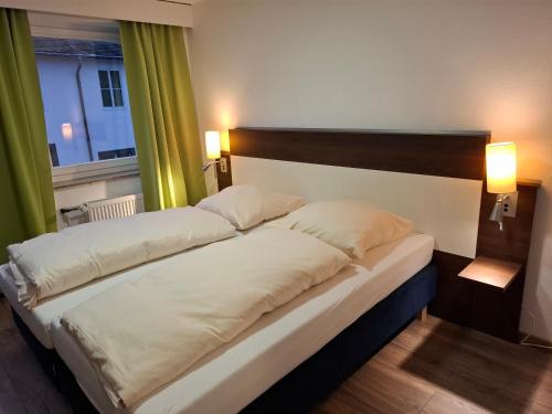 two beds in a hotel room with two lamps at Hotel Zens in Manderscheid