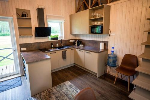 Holiday cabin 'CRANE' في Avotkalni: مطبخ بخزائن بيضاء وطاولة عمل