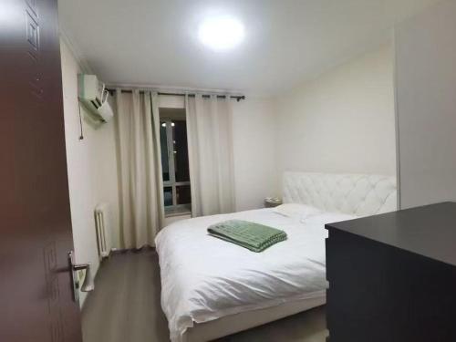 ein Schlafzimmer mit einem weißen Bett mit einem grünen Handtuch darauf in der Unterkunft Shoucheng international 2104 in Peking