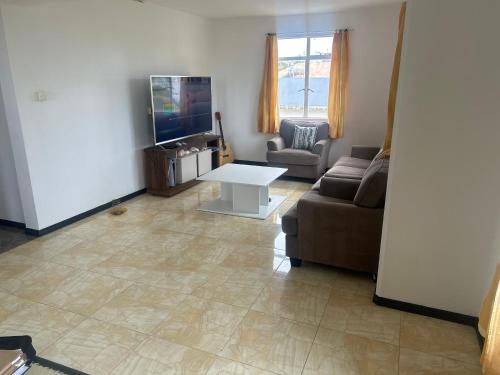 a living room with a couch and a tv and a table at Coconut House in Albion