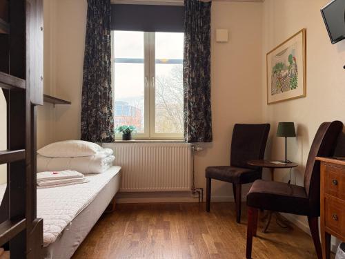 a bedroom with a bed and a window and a chair at Torget Vandrarhem in Kävlinge