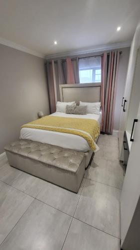 a bedroom with a large bed with a bench next to a window at The best uptown experience in the windy city in Gqeberha