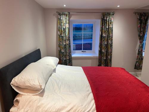 een slaapkamer met een bed met een rode deken en een raam bij Calsie Cottage, Clatt in Kirktown of Clatt